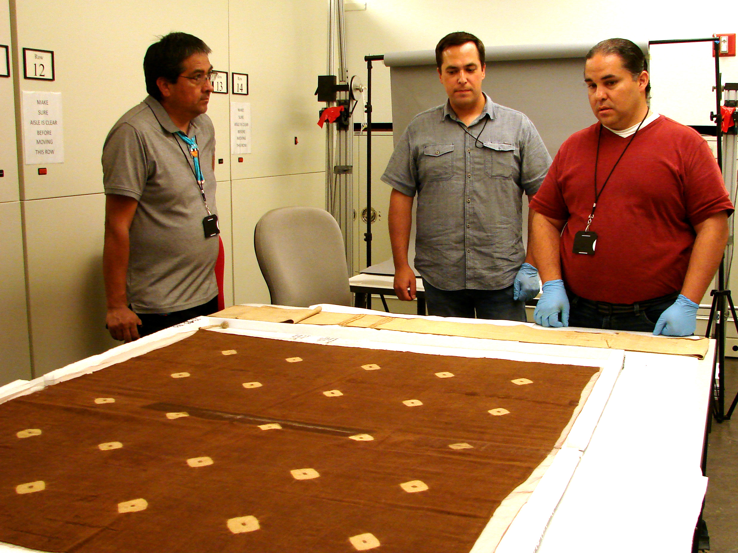 Team members Chris Lewis and Louie Garcia, joined by perishables specialist Dr. Edward Jolie, studying a cotton tie-dye blanket from Lake Canyon (Glen Canyon) at the Penn Museum in 2019. Courtesy, Penn Museum.